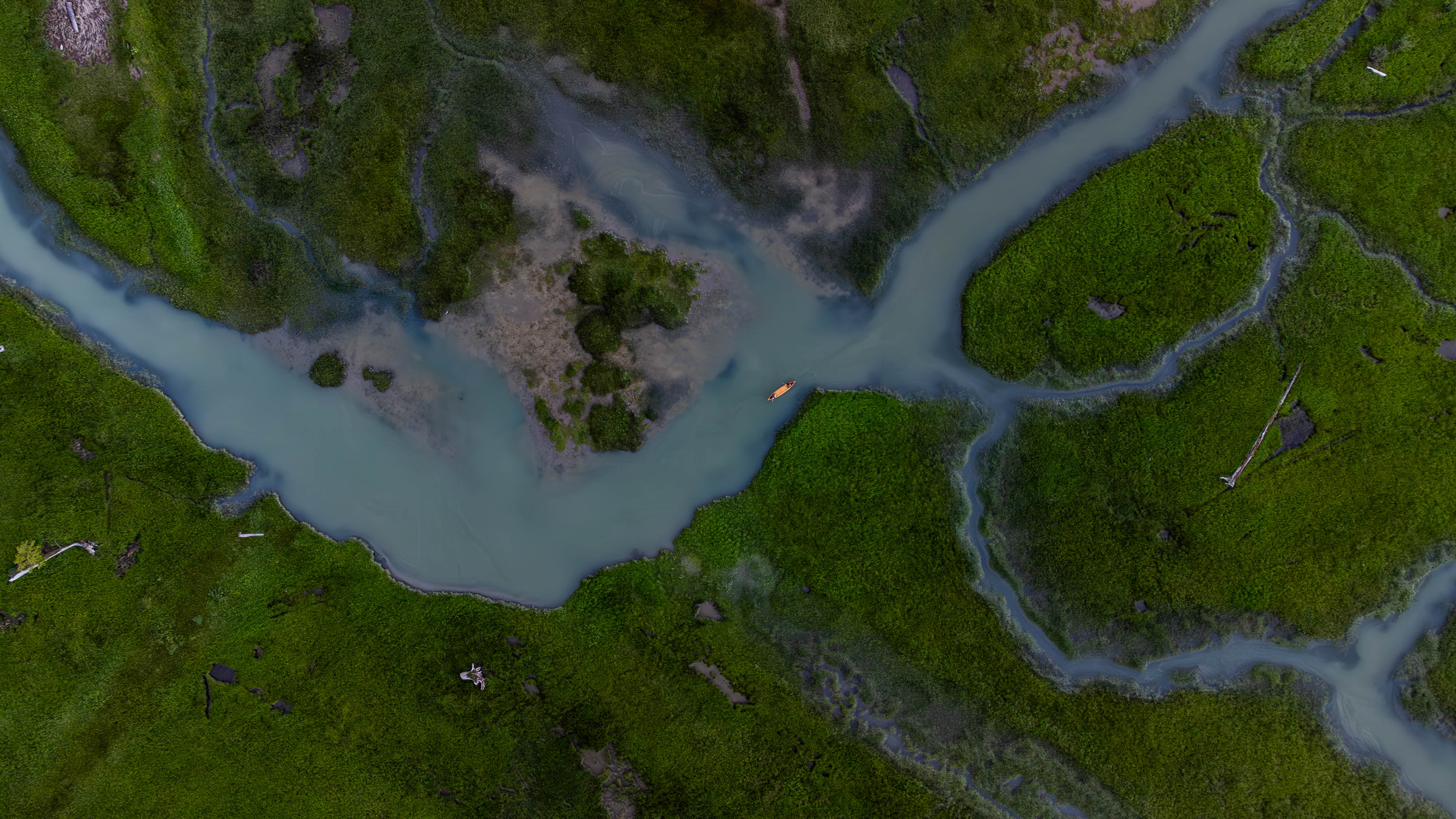 Aerial view of boat on turquoise Squamish River as an alternative to driving the Sea to Sky Highway